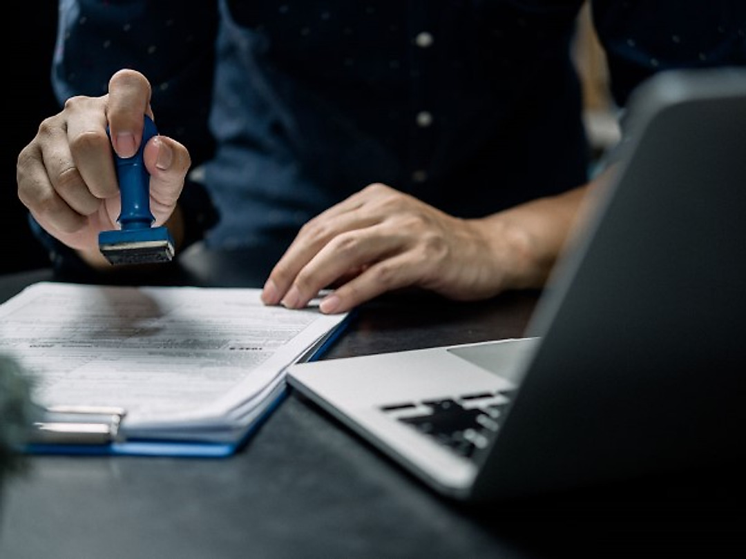 Un timbro apposto su un documento accanto a un computer portatile