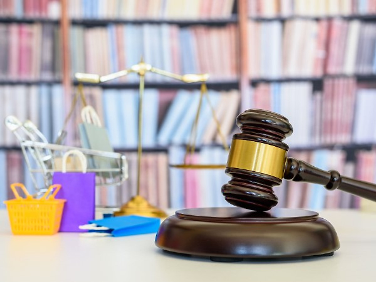 Un martelletto da giudice, una bilancia e alcuni cestini della spesa
